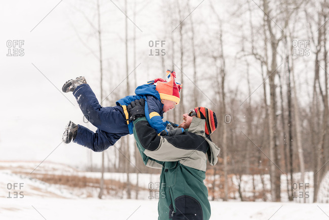Father lifting toddler in the air in winter outdoors