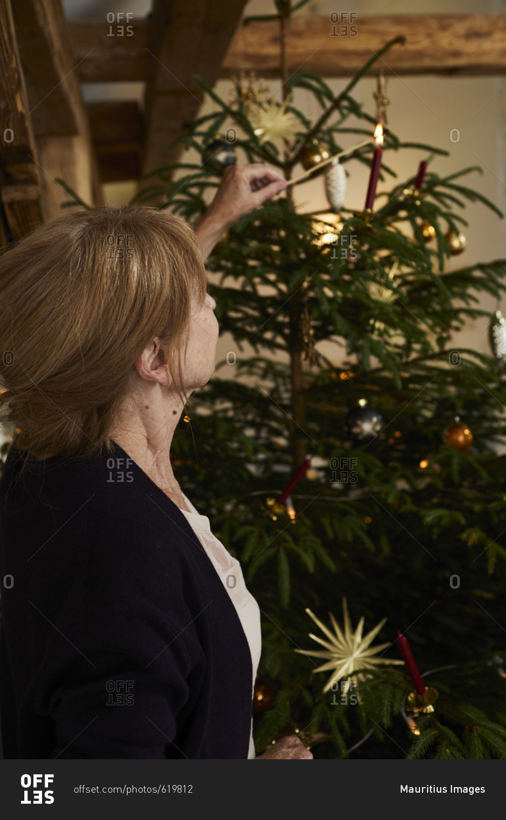 Woman lights candles on Christmas tree, Christmas Eve