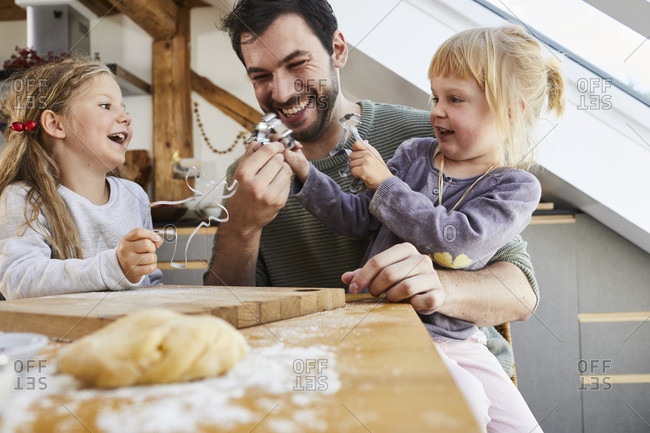 Family baking Christmas cookies, father and daughters having fun,