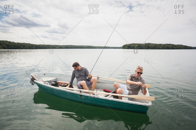 Two caucasian men are preparing their equipment for fly fishing from a boat on lake