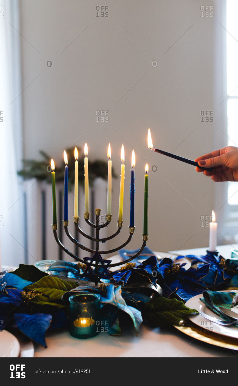 Person lighting menorah on table