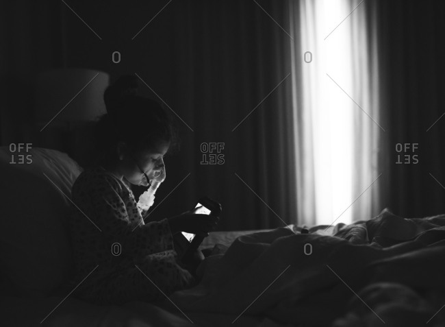 Girl sitting in bed using respiratory machine