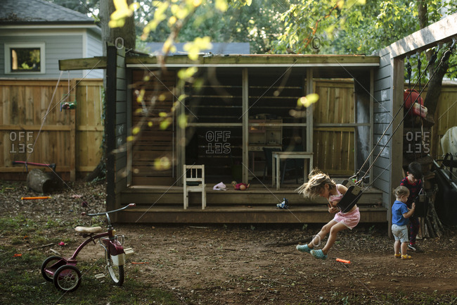 Children swinging and playing in a backyard playhouse