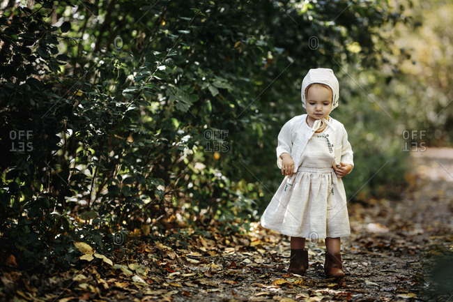 Girl with bonnet walks in leaves