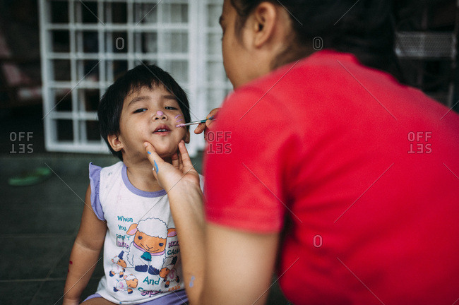 Woman painting a child's face with face paint