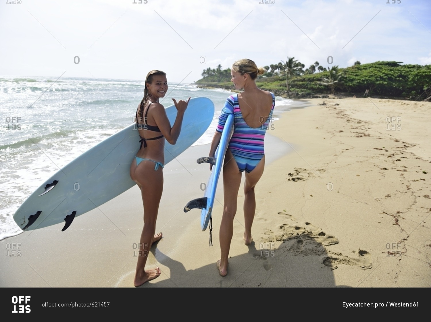 Two women running on the beach with surfboards