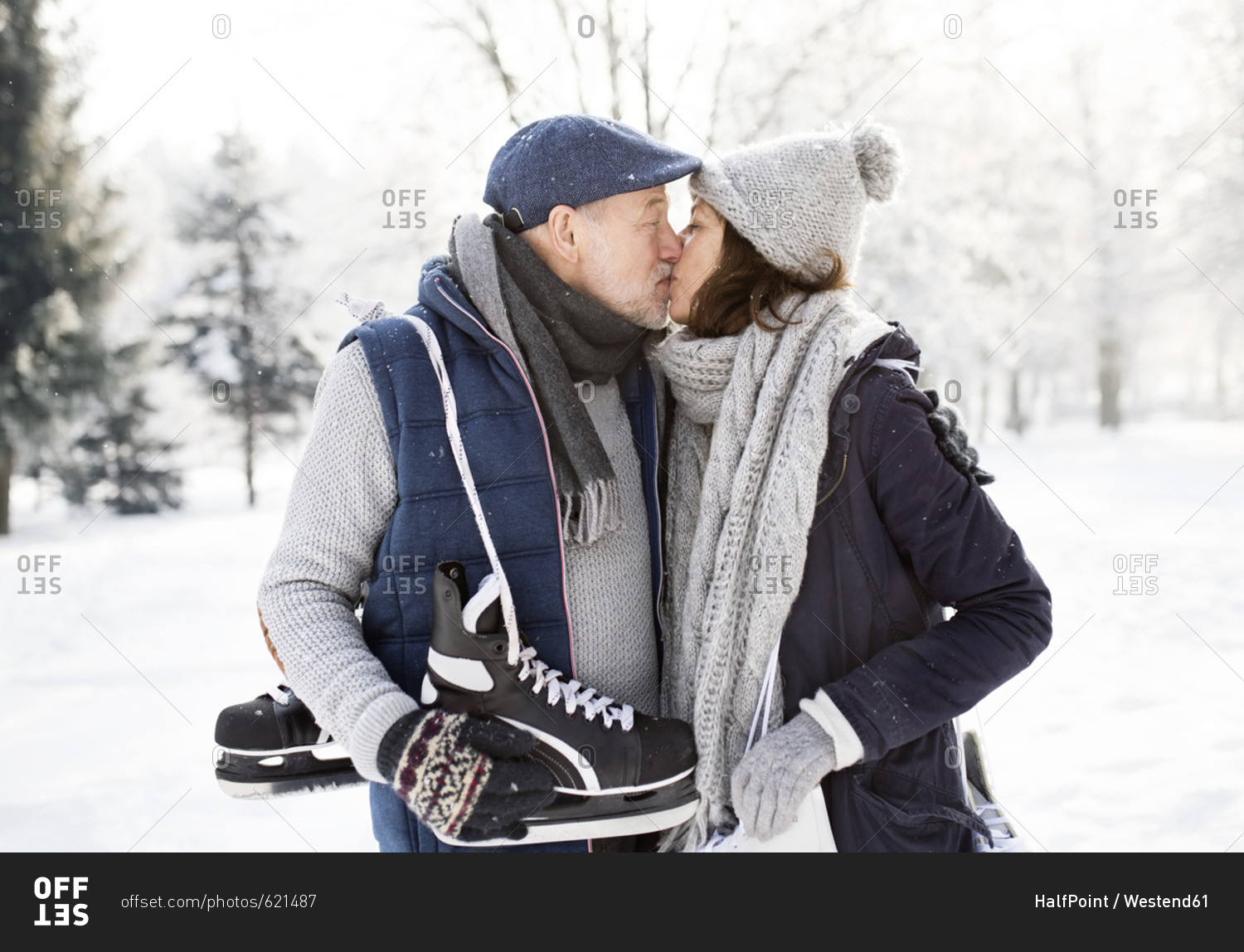 Senior couple with ice skates kissing in winter landscape