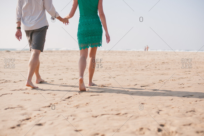 Barefoot couple walks on beach
