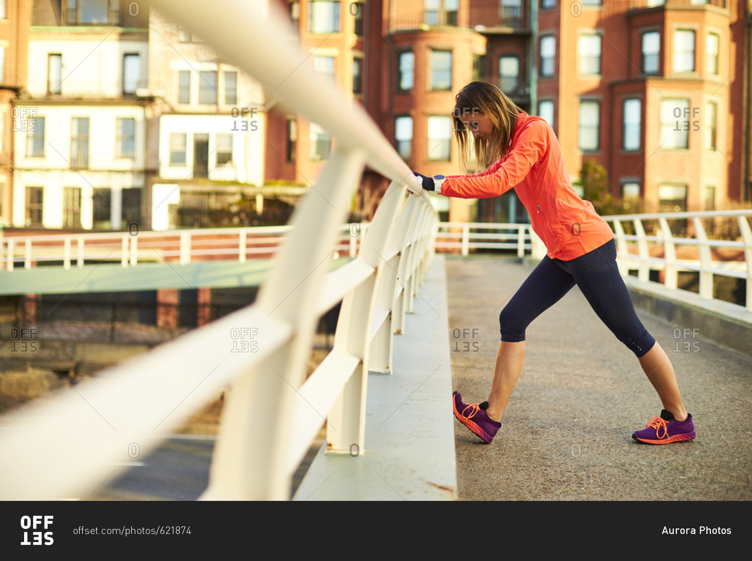 Woman stretching outdoors on bridge barrier, Boston, Massachusetts, USA