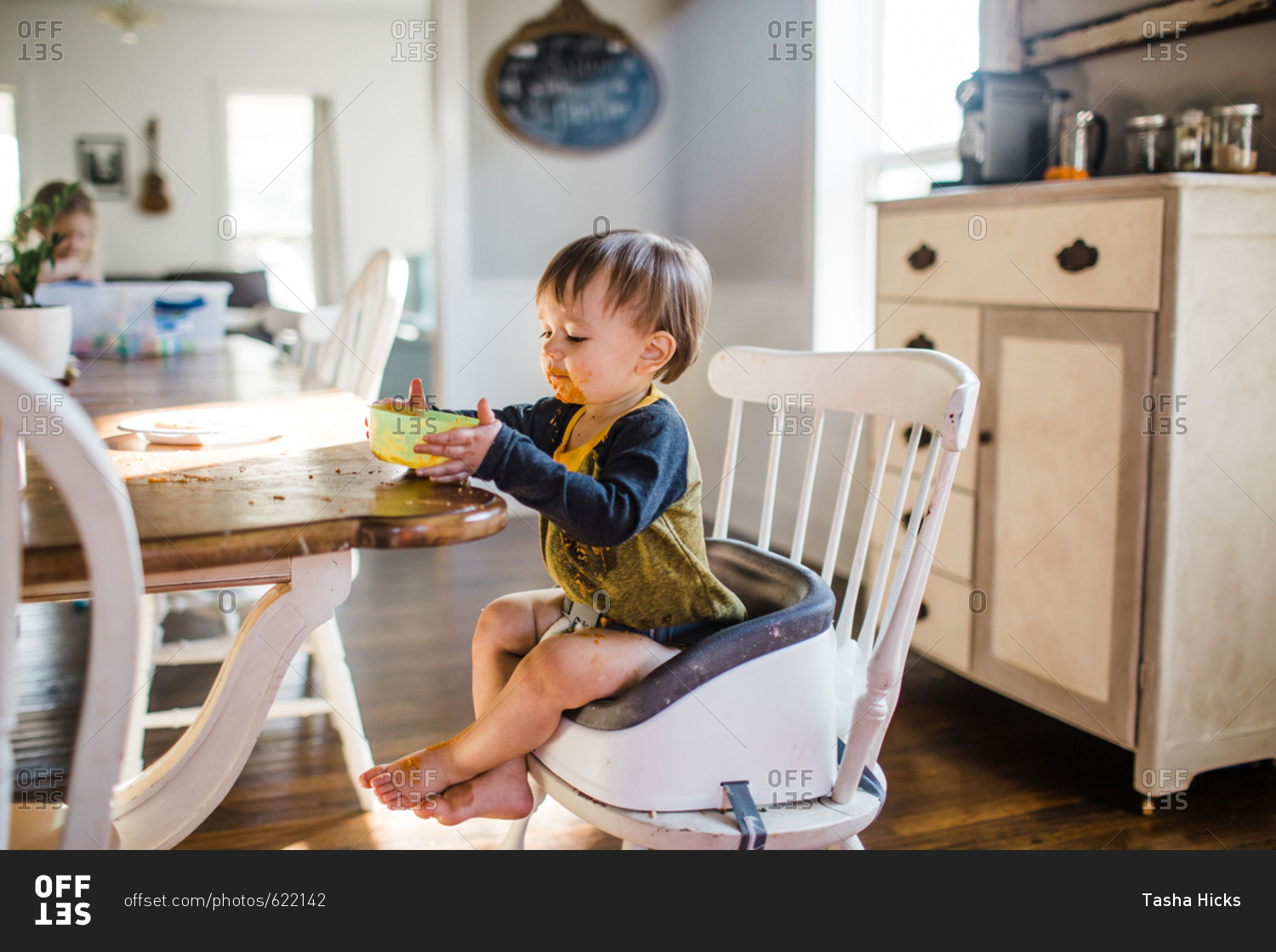 Messy toddler boy eating dinner in a booster seat