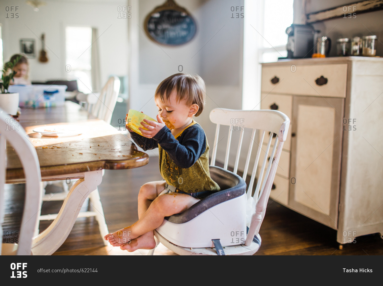 Messy toddler boy eating lunch in a booster seat