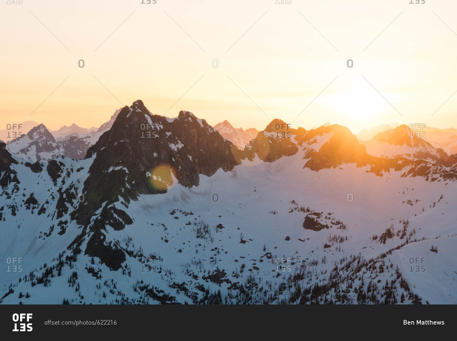 Bright sun seen from behind snow covered mountains