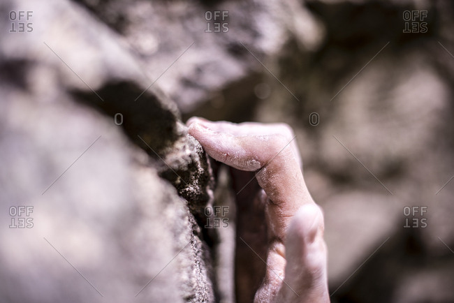 Close-up of cropped hand gripping on rock while bouldering
