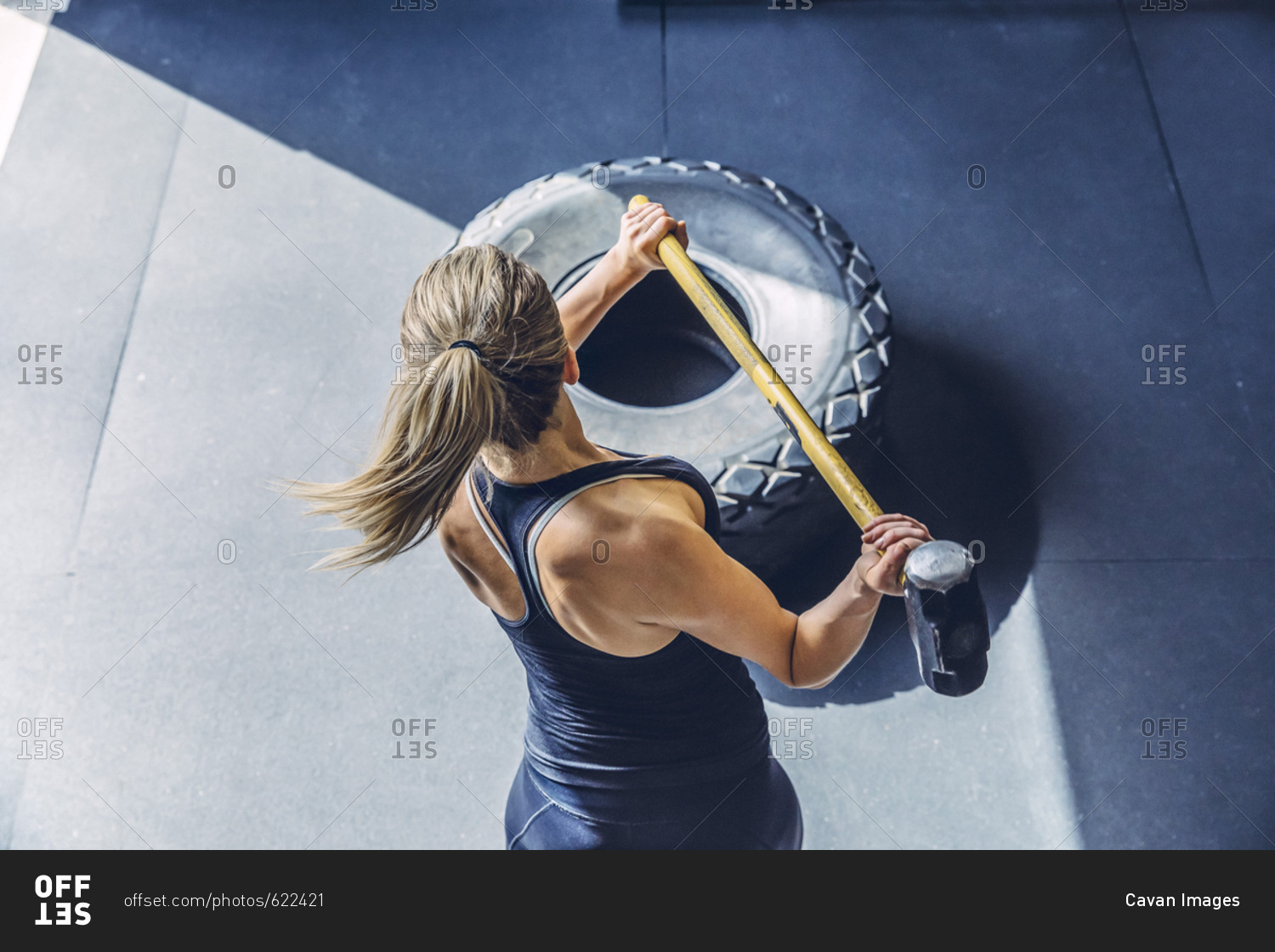 High angle view of woman hammering tire while exercising in gym