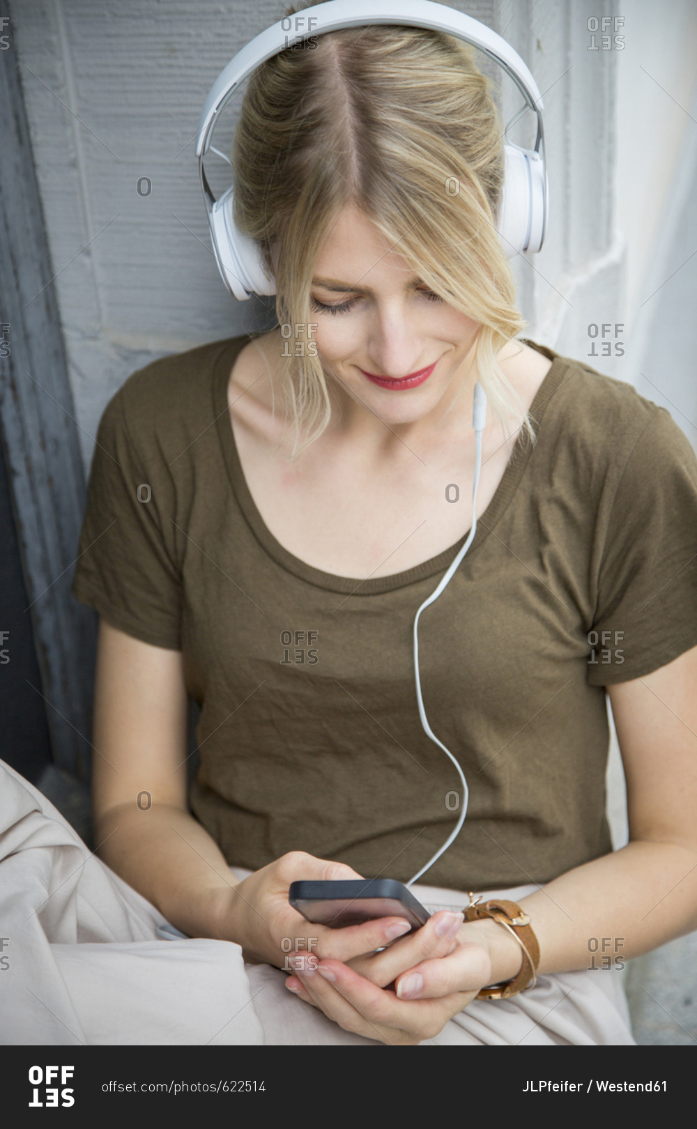 Relaxed young woman listening music with headphones and cell phone