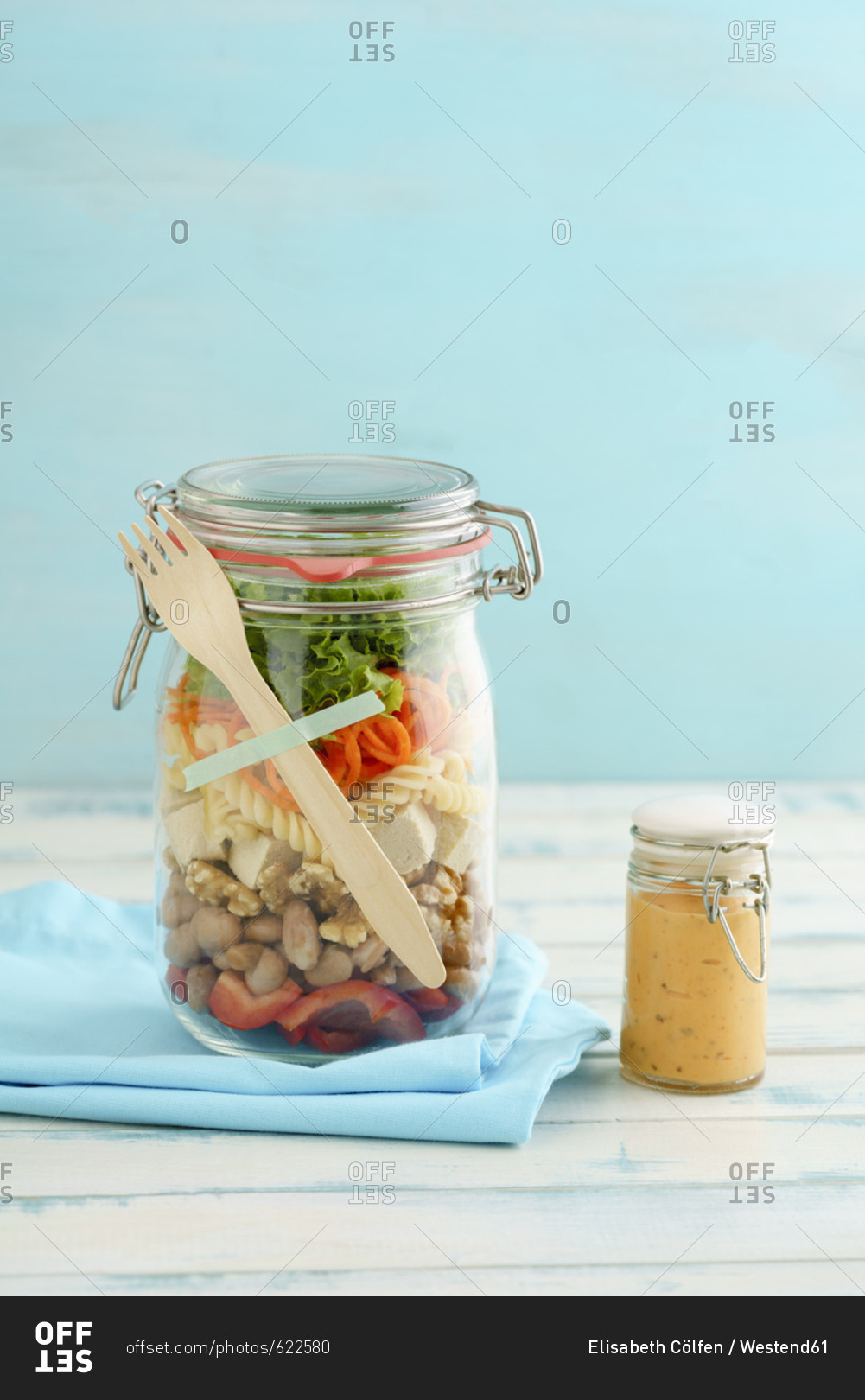 Preserving jar of vegan mixed salad with tofu and pasta and jar of cocktail sauce