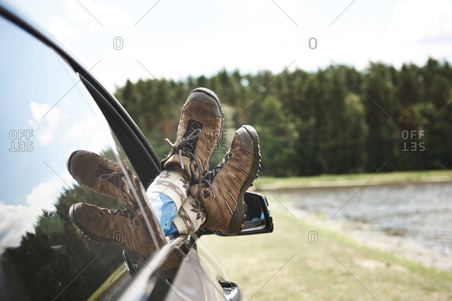 Woman relaxing in car, feet through open window, focus on feet