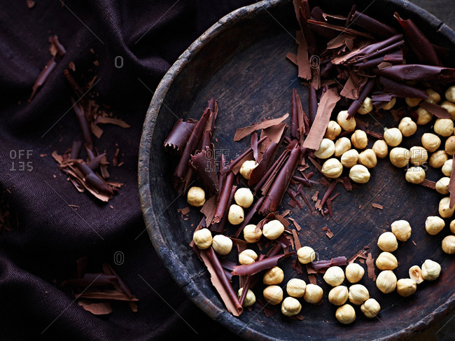 Chocolate shavings and hazelnuts in bowl, overhead view