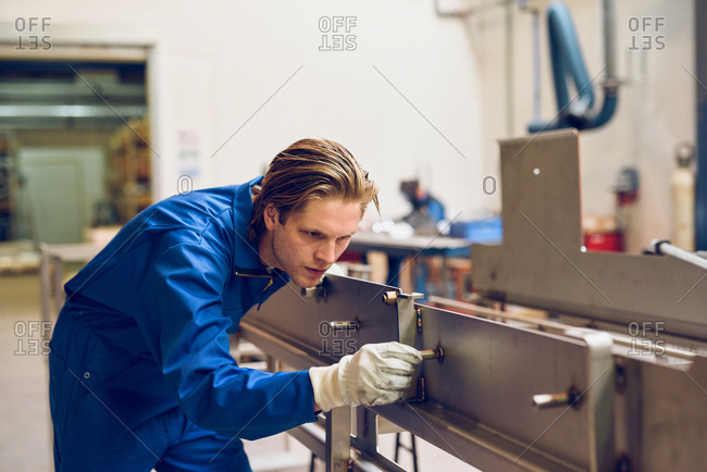 Factory worker wearing protective clothing, adjusting manufacturing machine part