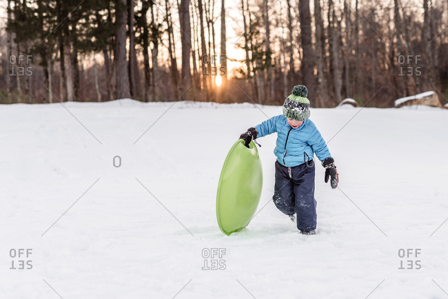Young boy playing with a sled in the snow