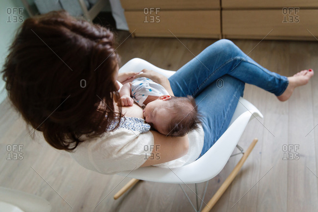 Mother sitting in rocking chair breastfeeding baby