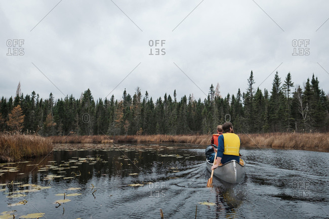 Paddling in a canoe through a marshy river under a cloudy fall sky