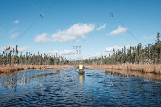 Paddling through marshy river under bright midday sun in fall