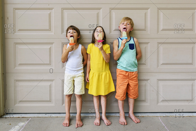 Three young kids eating popsicles in the summer