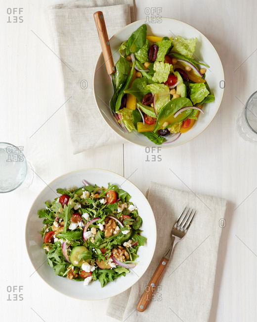 Two fresh salads overhead on a white washed wood surface from overhead