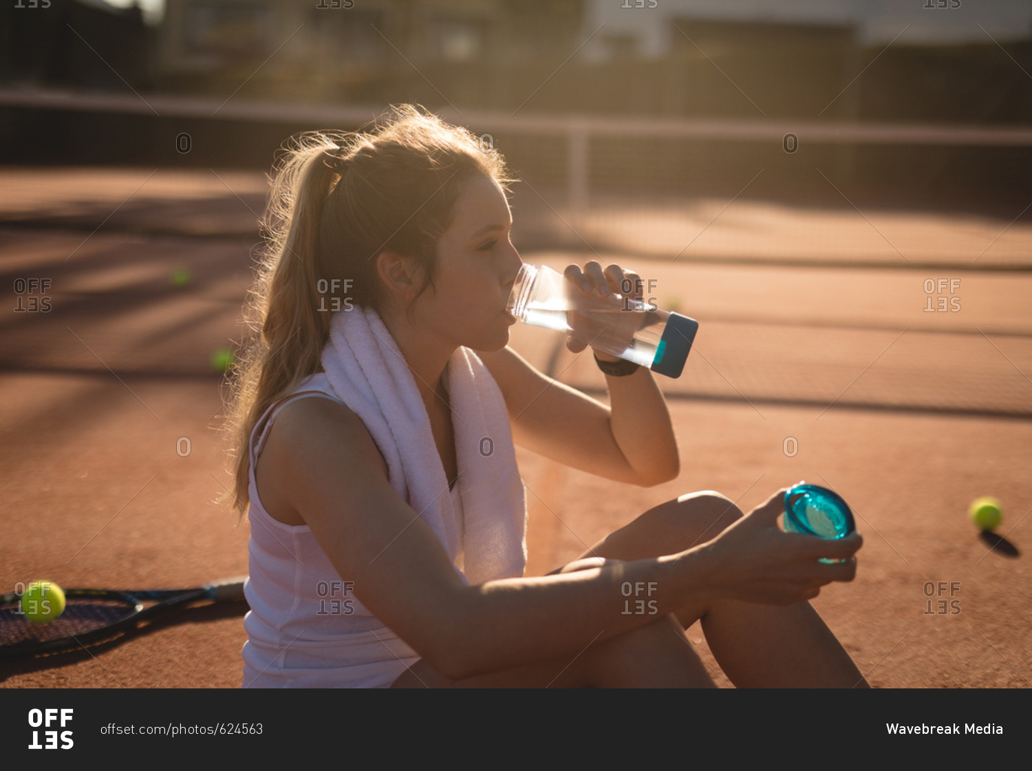 Tennis player drinking water after workout on a sunny day