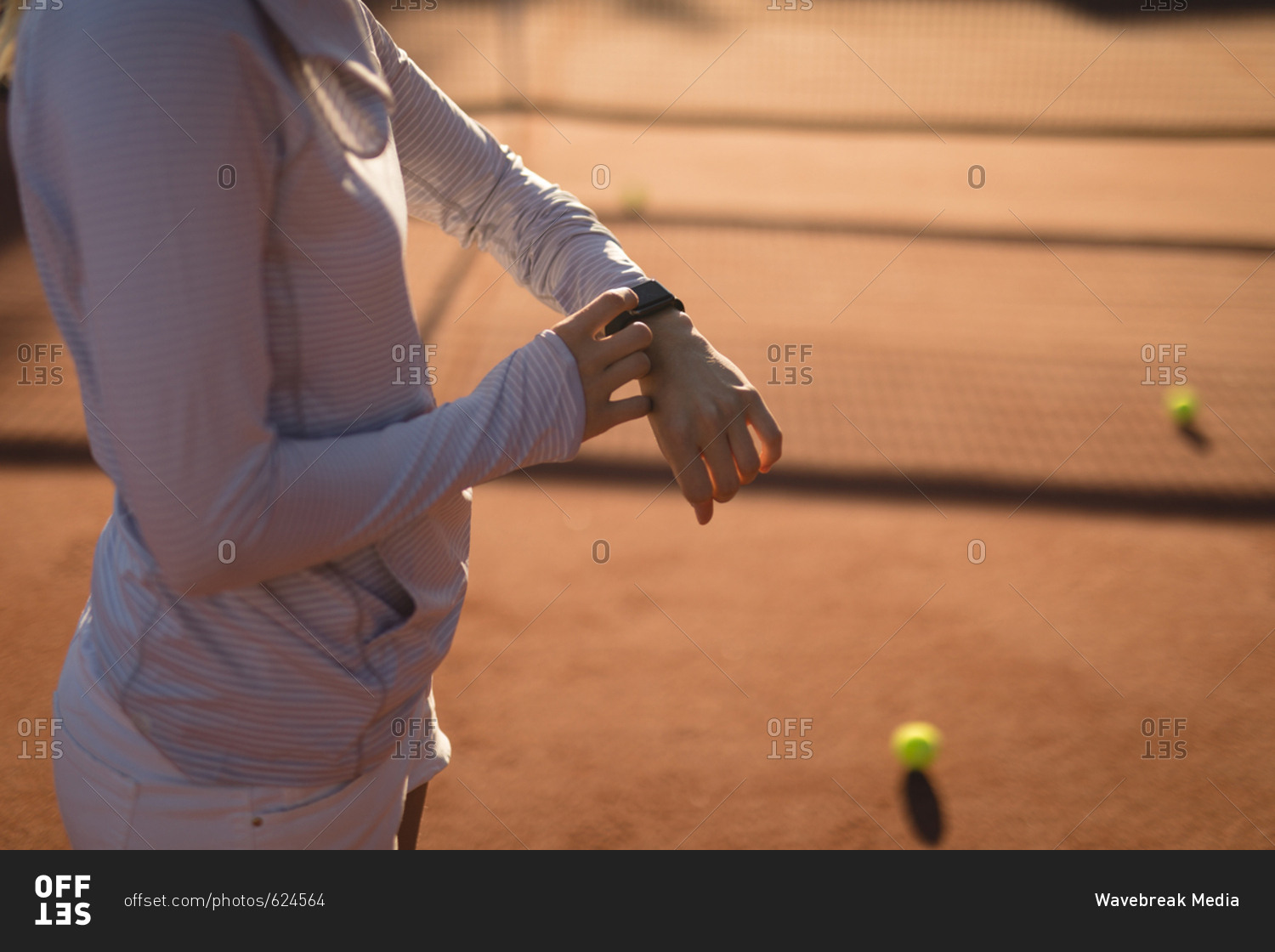 Mid section of tennis player using smart watch in ground on a sunny day