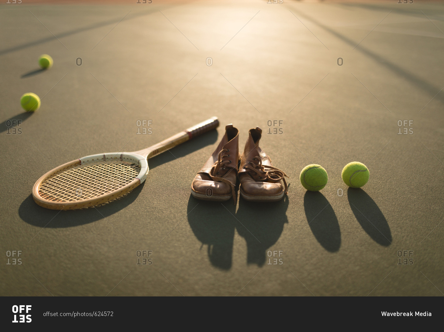 Tennis ball, sports shoes and racket in ground on a sunny day