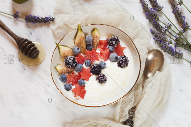 Bowl of Greek yoghurt with fig- watermelon- frozen berries and lavender honey