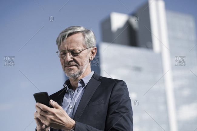 Grey Haired Businessman Typing Into Smartphone Stock Photo Offset