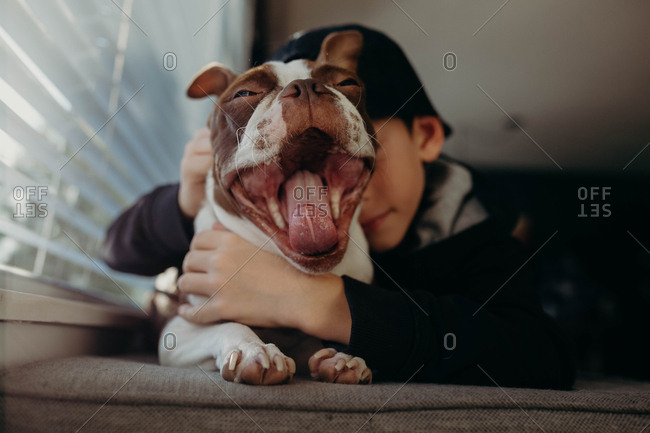 Boy hugging yawning dog - Offset