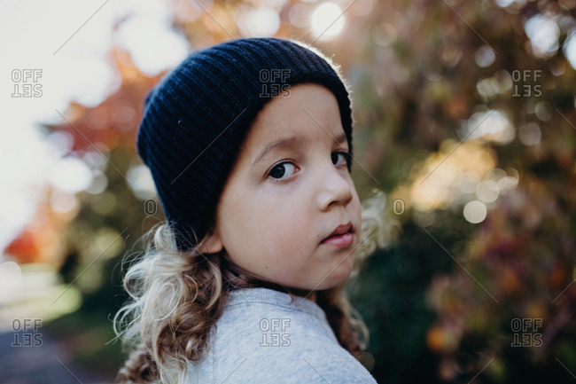 Portrait of a boy with long curly hair wearing a knit hat