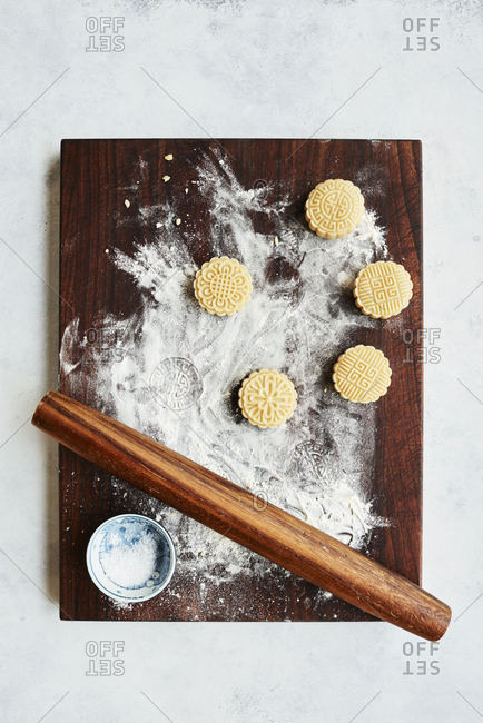 Mooncake cookies cut-outs on wooden cutting board with flour and rolling pin