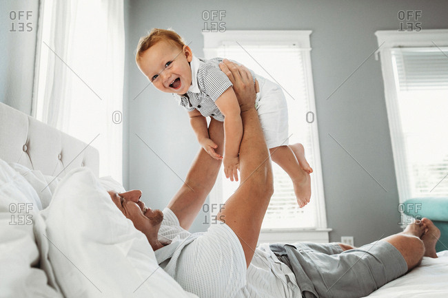 Father and baby smile together while playing in bed