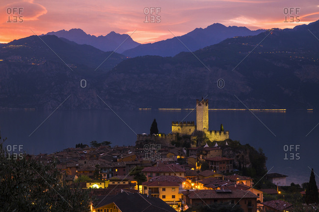 Lake Garda, Italy - April 7, 2017: Verona, Italy - April 7, 2017: Verona, Italy - April 7, 2017: The medieval village and the castle of Scaligero di Malcesine light up soon after a fiery sunset on Garda lake
