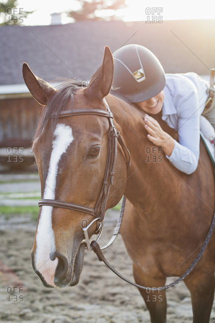 Rancher lying on horse while riding at stable