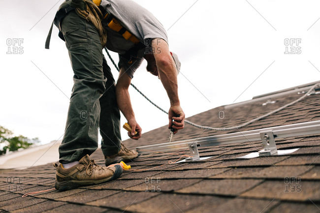 Construction worker on a roof installing solar panel components