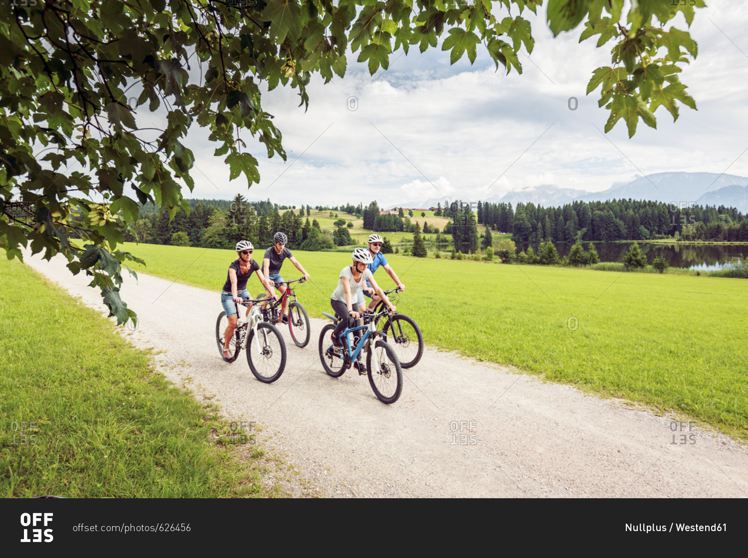 Germany- Bavaria- Pfronten- family riding mountain bikes at ladeside