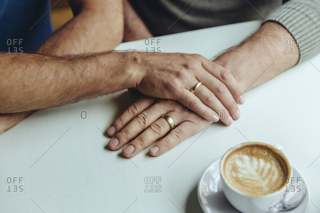Close-up of men's hands with wedding rings and a cup of coffee