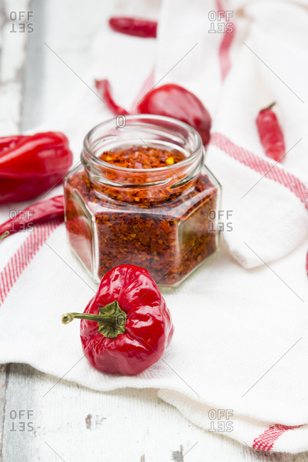 Glass of chili flakes and red chili pods on kitchen towel