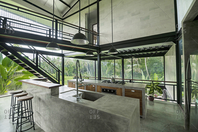 Modern minimalist kitchen in contemporary design house with glass facade surrounded by lush tropical garden