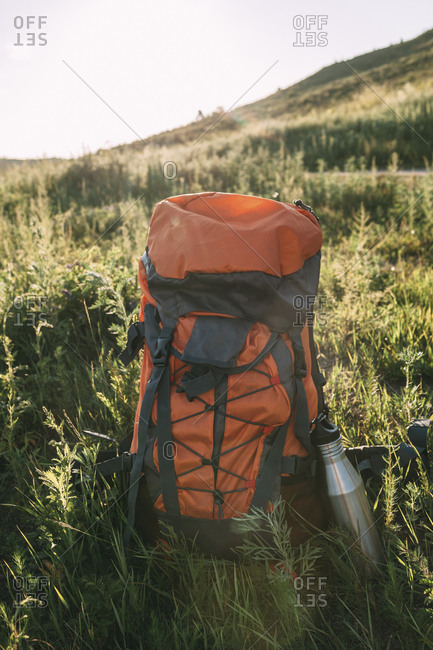 Backpack and thermos flask on a meadow
