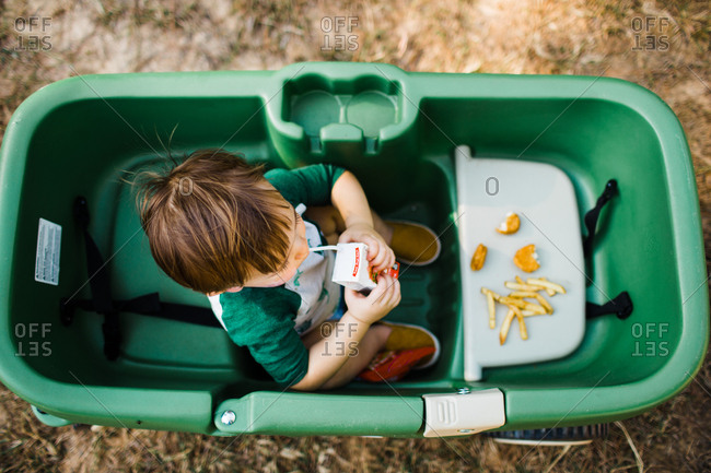 Little boy sitting in a wagon eating