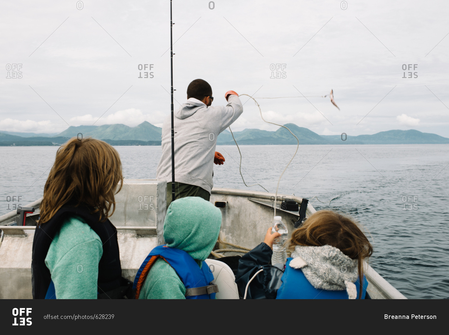 Children watching their father cast a rope into the water while deep water fishing
