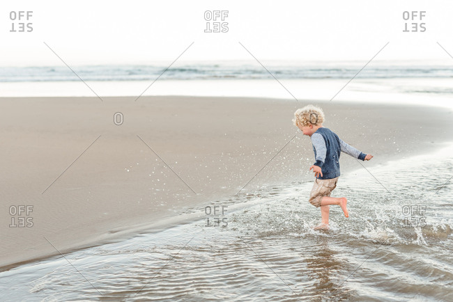 Little boy running in the crashing tide on the beach