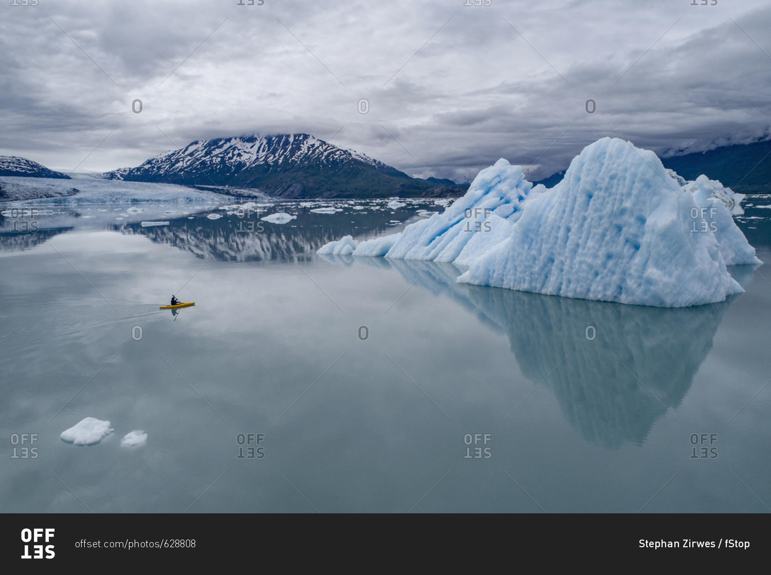 Person canoeing in lagoon by icebergs against cloudy sky, Lake George, Palmer, Alaska, USA